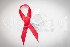 Red Aids ribbon beside condom
