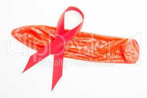Red awareness ribbon lying on condom