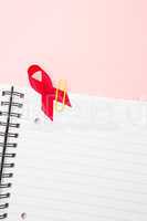 Awareness ribbon for aids clipped onto notepad