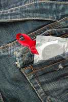 Condom in jeans pocket with red awareness ribbon