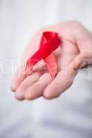 Man holding out red aids awareness ribbon