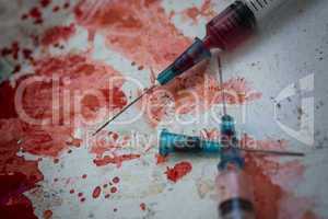 Two syringes lying on blood splatter