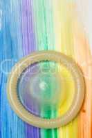 Rolled up condom on rainbow brush stroke