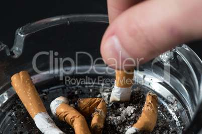 Hand putting out a cigarette in ashtray