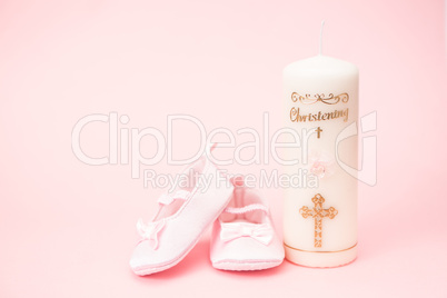 Christening candle with pink baby booties and copy space