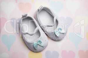 Baby blue booties on heart pattern background