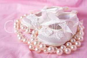 White baby booties with string of pearls