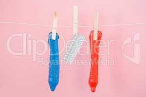 Contraceptive pill and condoms hanging from line