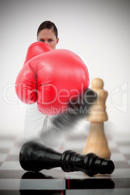 Woman in boxing gloves knocking over chess pieces