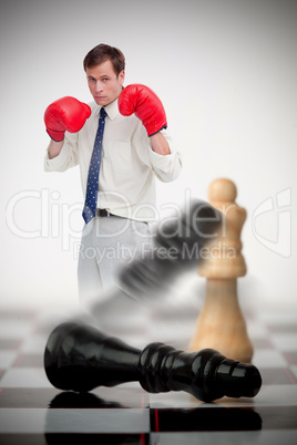 Businessman in boxing gloves knocking over chess pieces