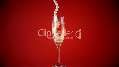 String of pearls falling into champagne flute
