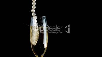 Pearl necklace falling into champagne