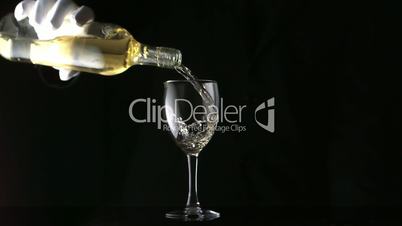Gloved hand pouring white wine into glass