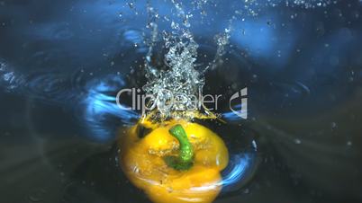 Yellow capsicum falling into water