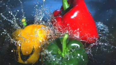 Three peppers falling into water