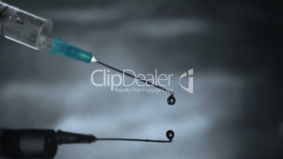Drop from syringe falling in grey water