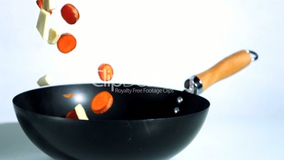 Chopped carrots and parsnips falling into wok