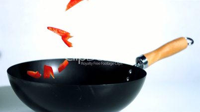 Sliced red pepper falling into wok