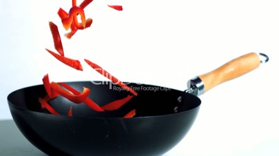 Sliced red peppers falling into wok