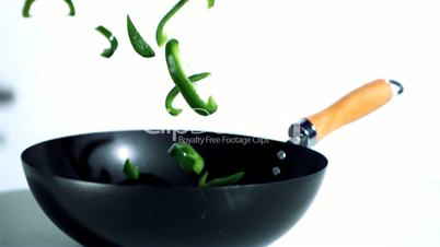 Sliced green peppers falling into wok