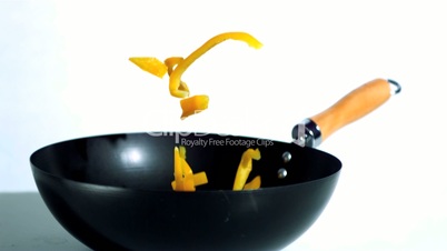Sliced yellow pepper falling into wok