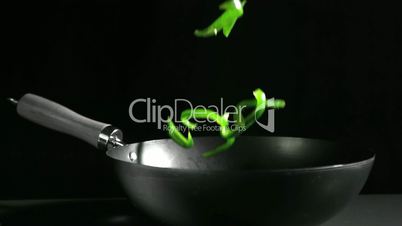 Sliced green pepper falling into wok