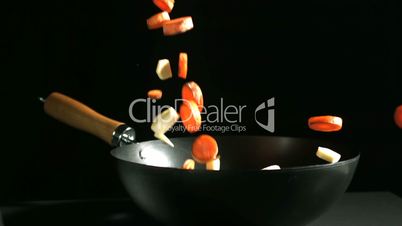Chopped carrots and parsnips falling into a wok