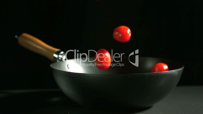 Cherry tomatoes falling into wok