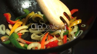 Wooden fork mixing vegetables in wok