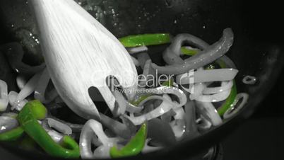 Wooden fork mixing vegetables in wok in black and white