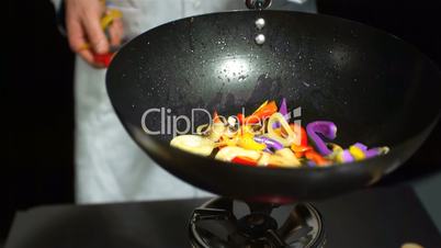Chef tossing mixed vegetables in a wok