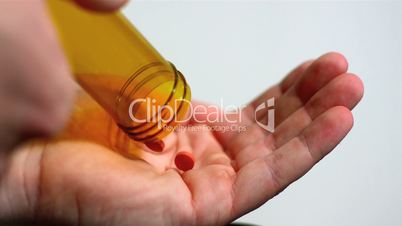 Two red tablets being poured into open palm