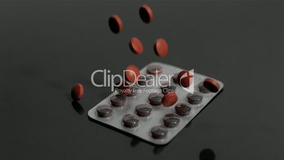Red tablets falling onto empty blister pack