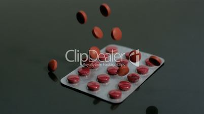 Red tablets falling onto blister pack