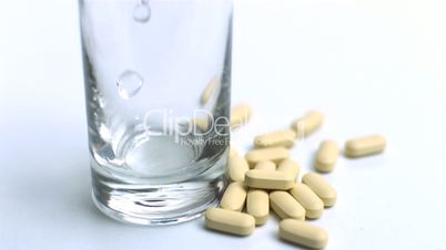 Water filling glass beside medicine