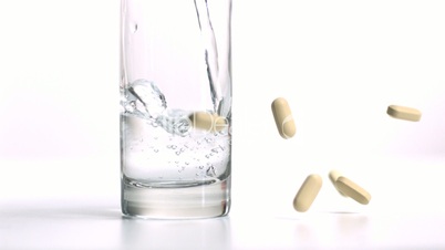 Pills falling and glass of water being filled