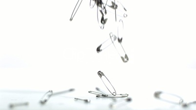 Safety pins falling on white background