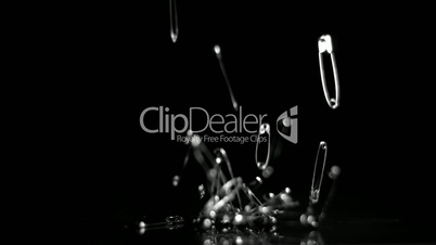 Many safety pins crashing to floor on black background