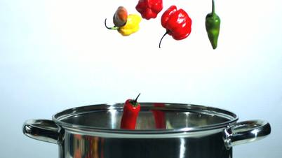 Various chilis falling in a pot