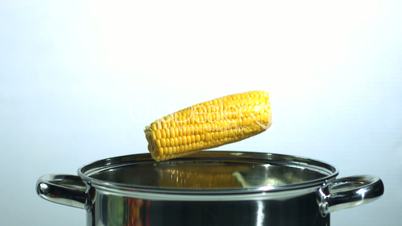 Two corn cobs falling into a saucepan