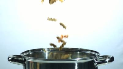 Tricolour fusilli falling into a saucepan