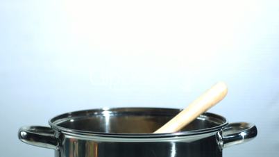 Wooden spoon falling in a saucepan