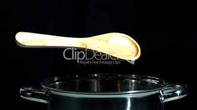 Wooden spoon falling in pot