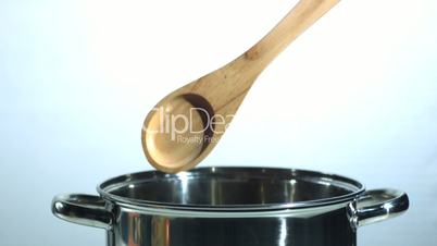 Wooden spoon falling in a pot