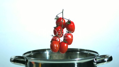 Vine tomatoes and parsnip falling in saucepan