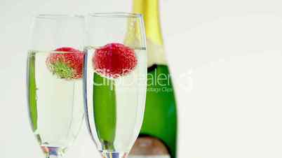 Strawberries falling into champagne flutes