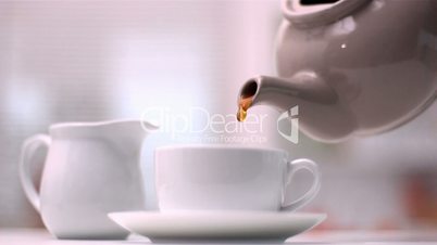 Teapot pouring tea into cup