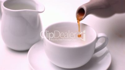 Teapot pouring tea into a cup