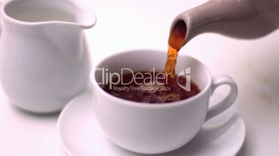 Tea being poured into cup by teapot