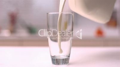 Milk pouring into glass in kitchen